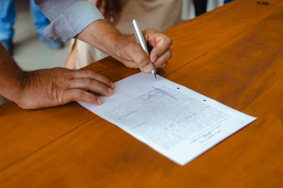 A couple's hands signing the IMM 5409 across a wooden desk, with a notary seal in the corner of the frame
