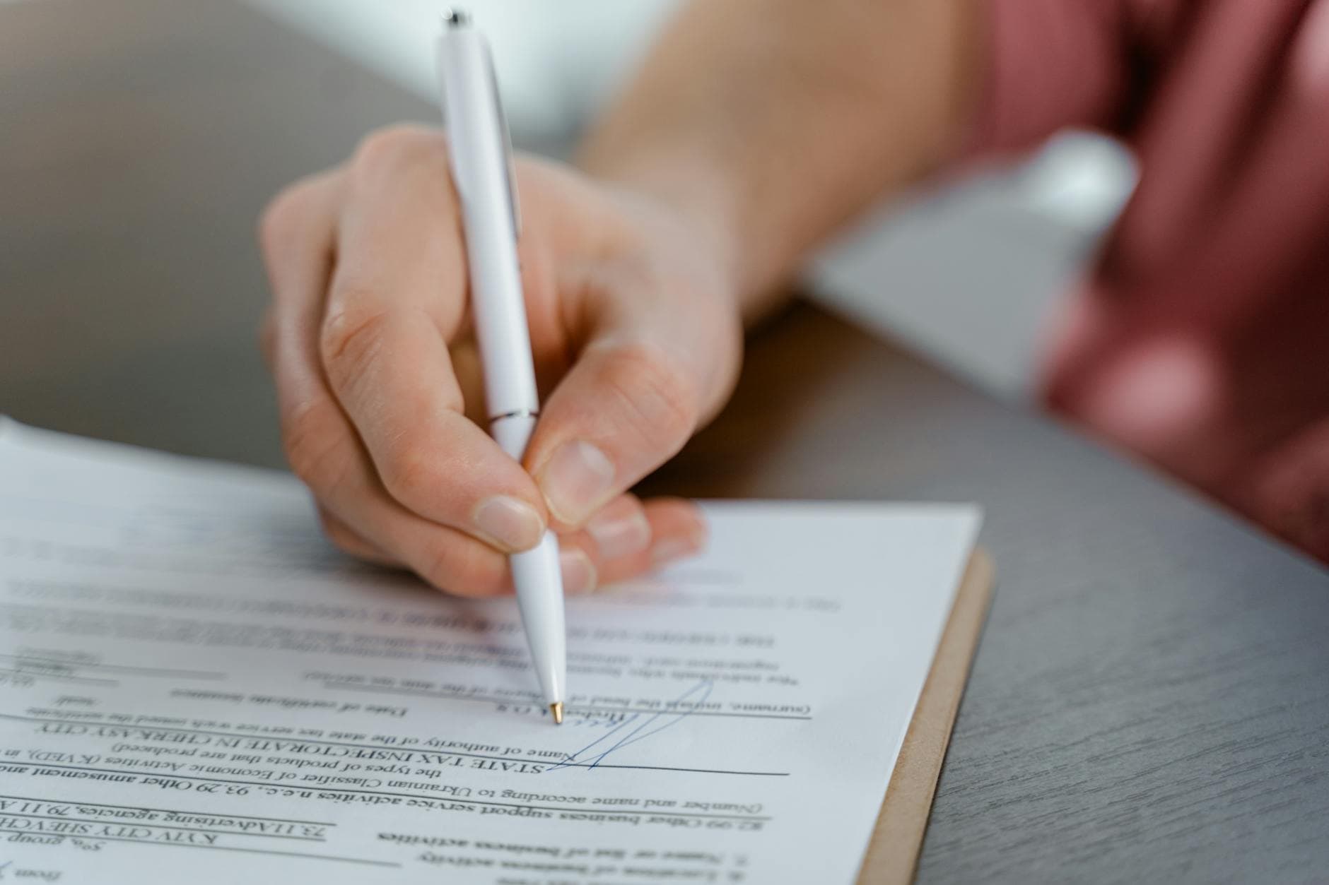 A notary public's desk in Ottawa with a printed travel consent letter, a passport open to the photo page, and a parent's pen mid-signature