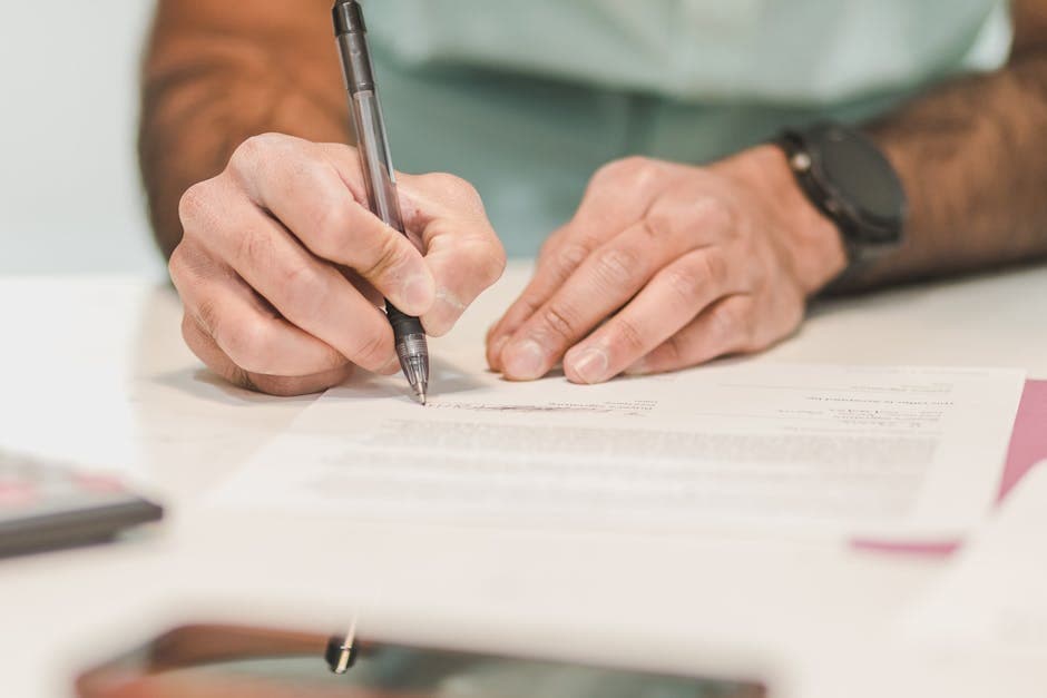 Client signing a sworn statement at a desk while the commissioner of oaths watches
